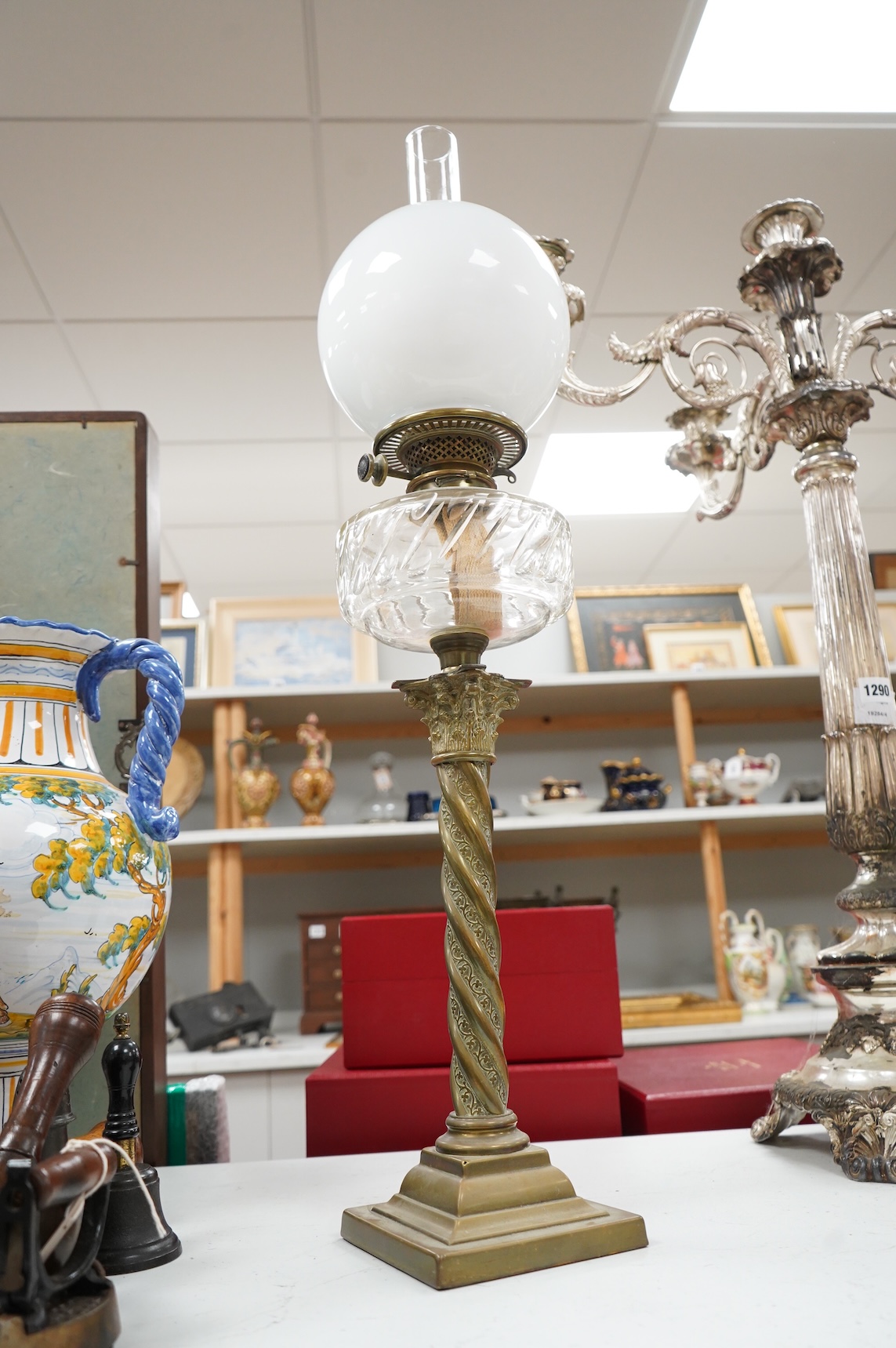 A brass corinthian column oil lamp with glass reservoir and opaque glass shade, 78cm high